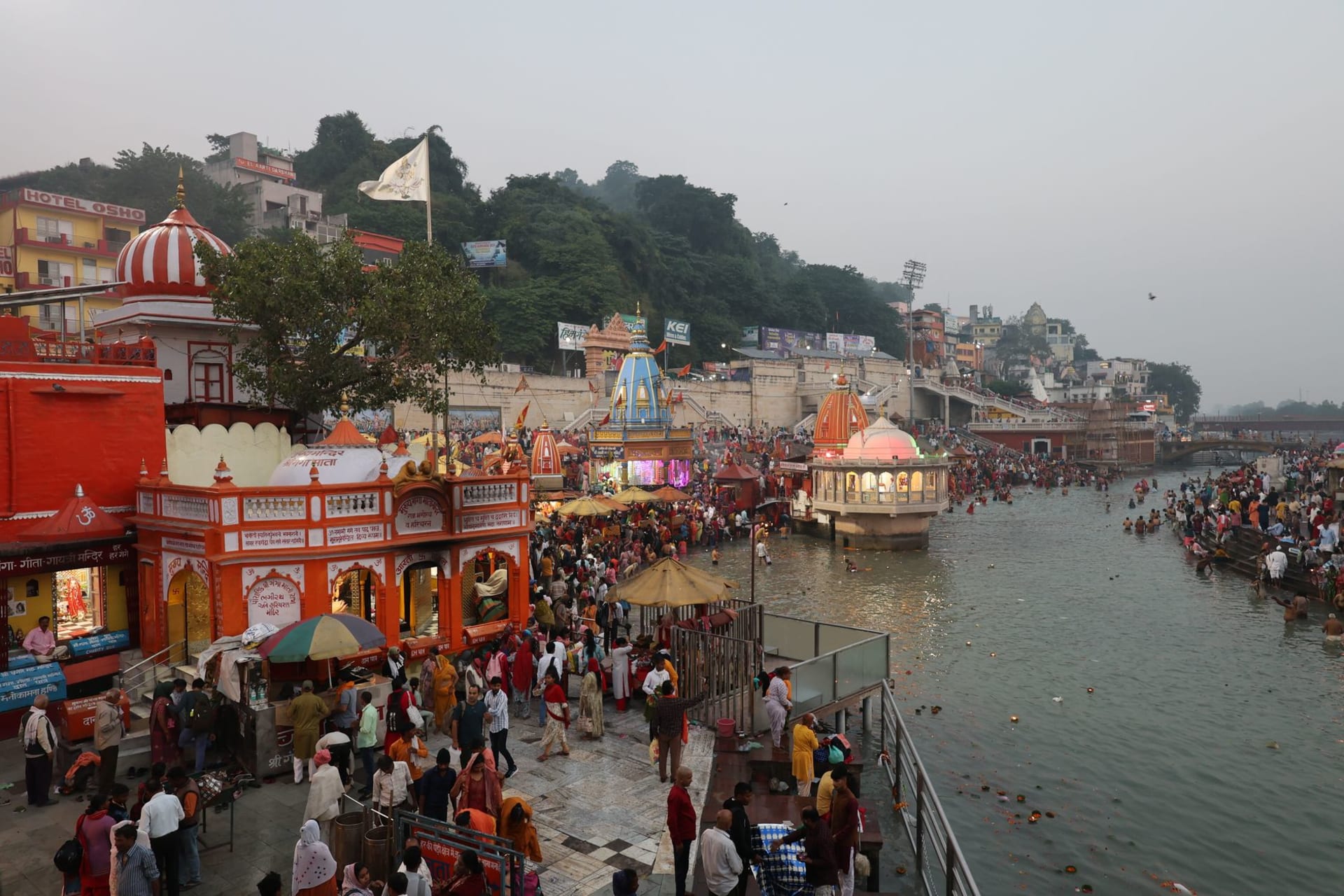 Har Ki Pauri ghat at night, dozens of oil-lamp diyas floating downstream on the black Ganges, devotees in white lining the steps