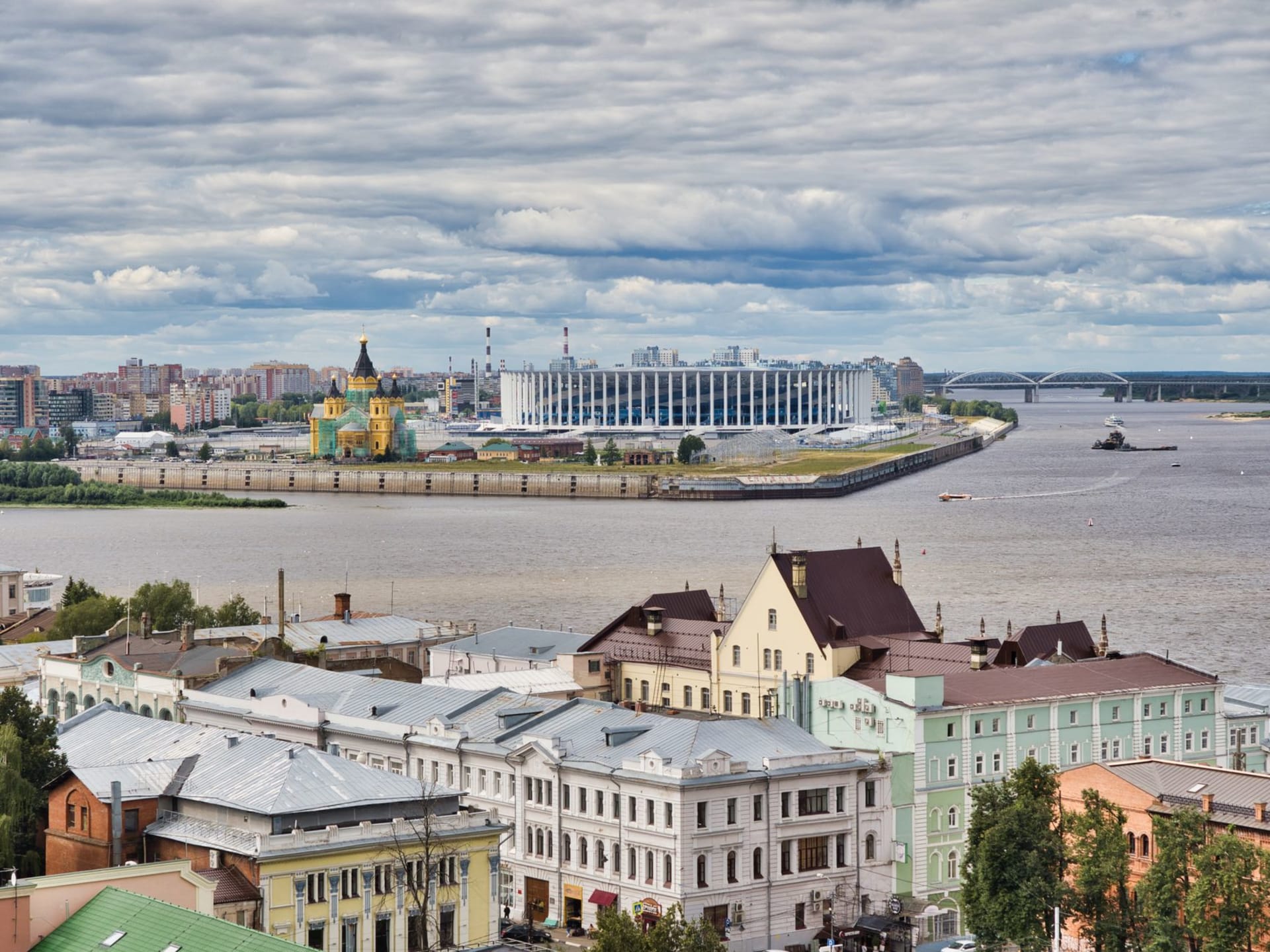 Saratov's Lipki Park in autumn with the classical facades of the old university quarter visible through gold and copper foliage, the Volga glinting in the far distance