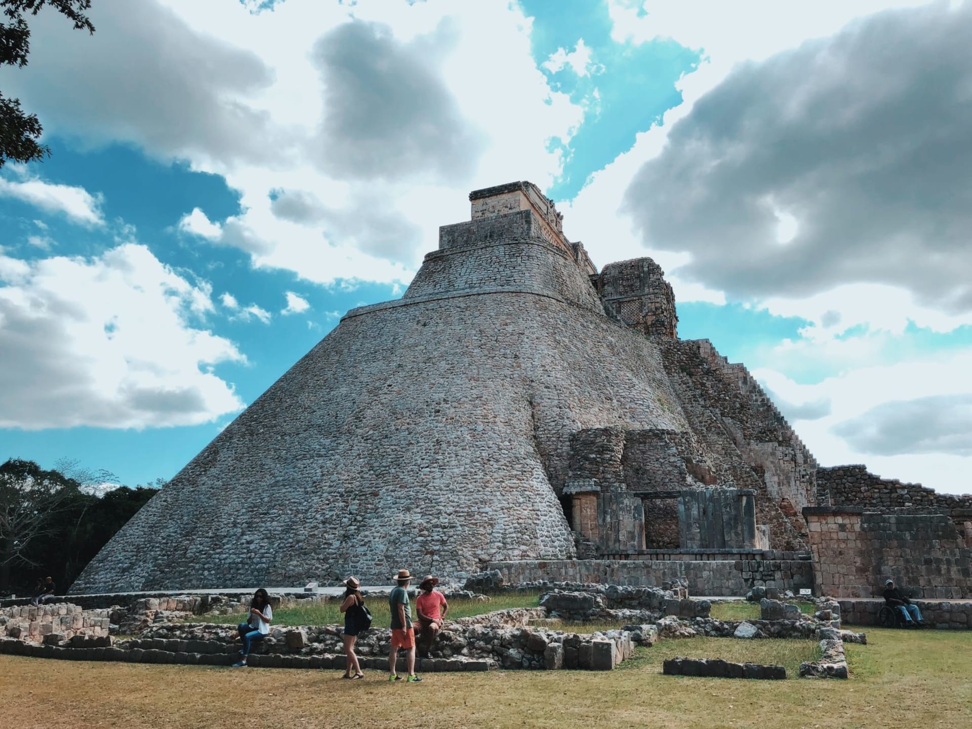 The Pyramid of the Magician at Uxmal rising above the Yucatan jungle, its unusual oval shape set against an evening sky, stone lattice carvings visible on the upper temple