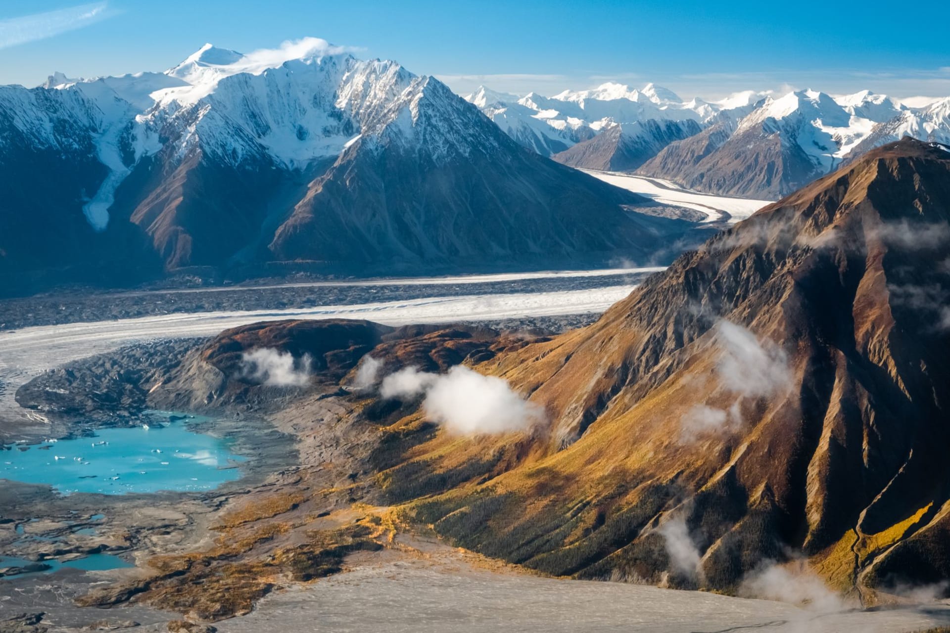 A low treeless tundra island with weathered wooden buildings beside a grey Arctic sea under a pale sky