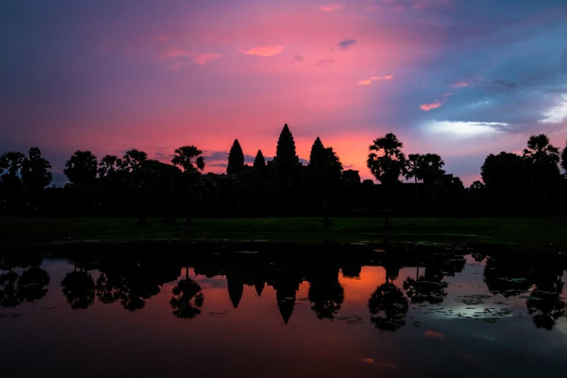 Angkor Wat silhouette reflected in still water at dawn