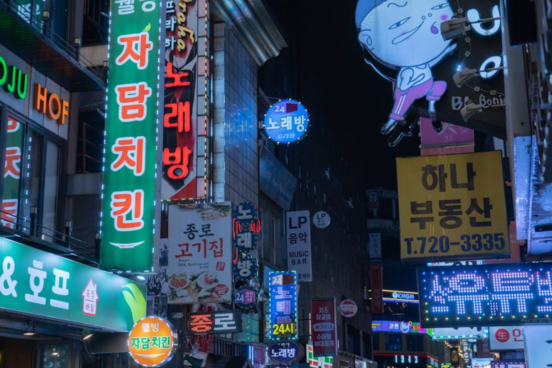 Neon-lit alley in Seoul at night with street food vendors and crowds