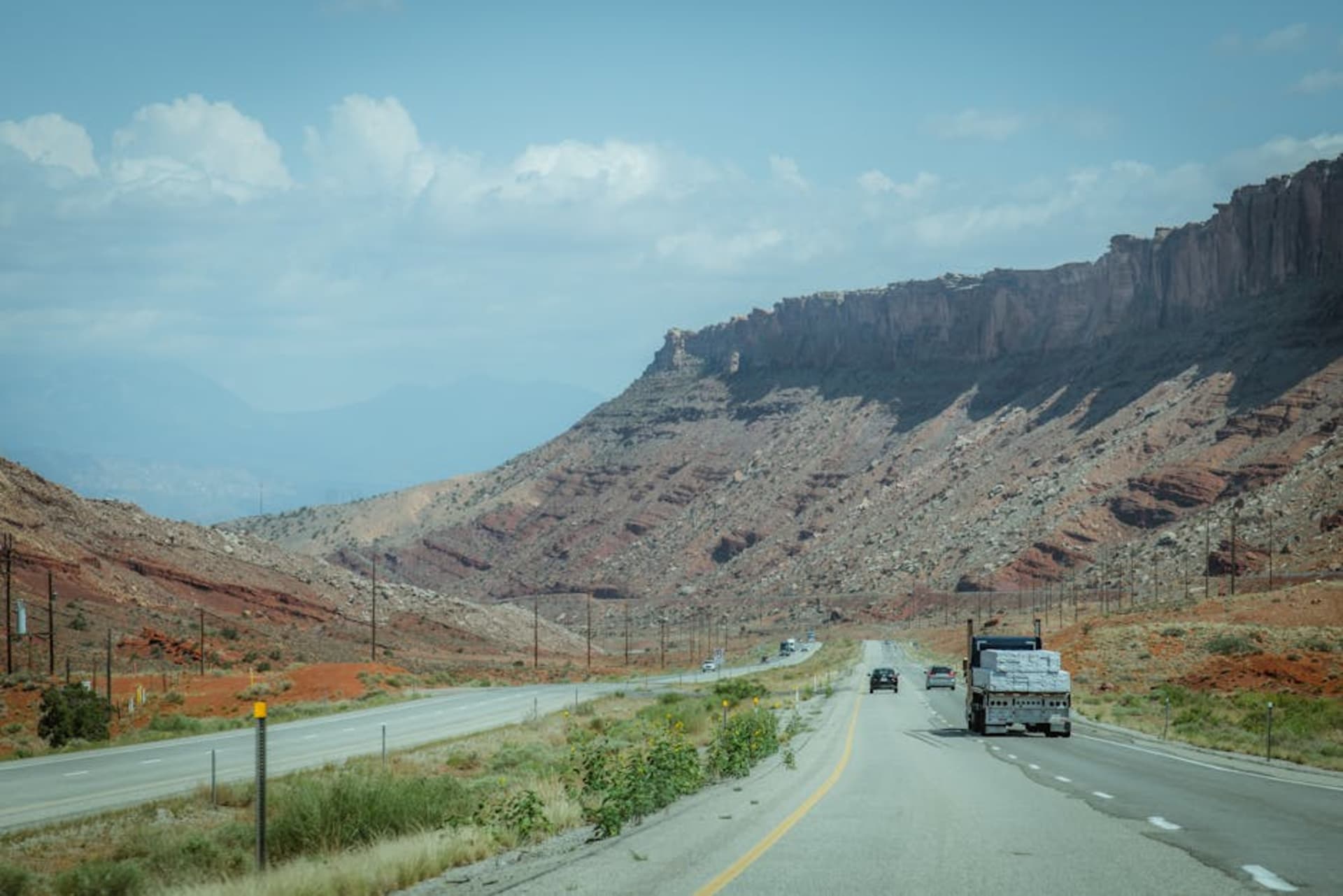 A desert highway stretching toward distant red rock mesas under a vast sky