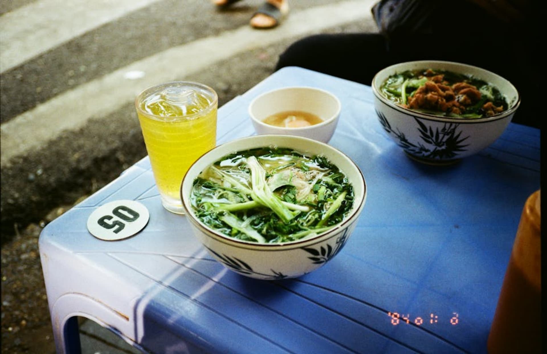 Street food scene in Hanoi with traditional pho and iced green tea