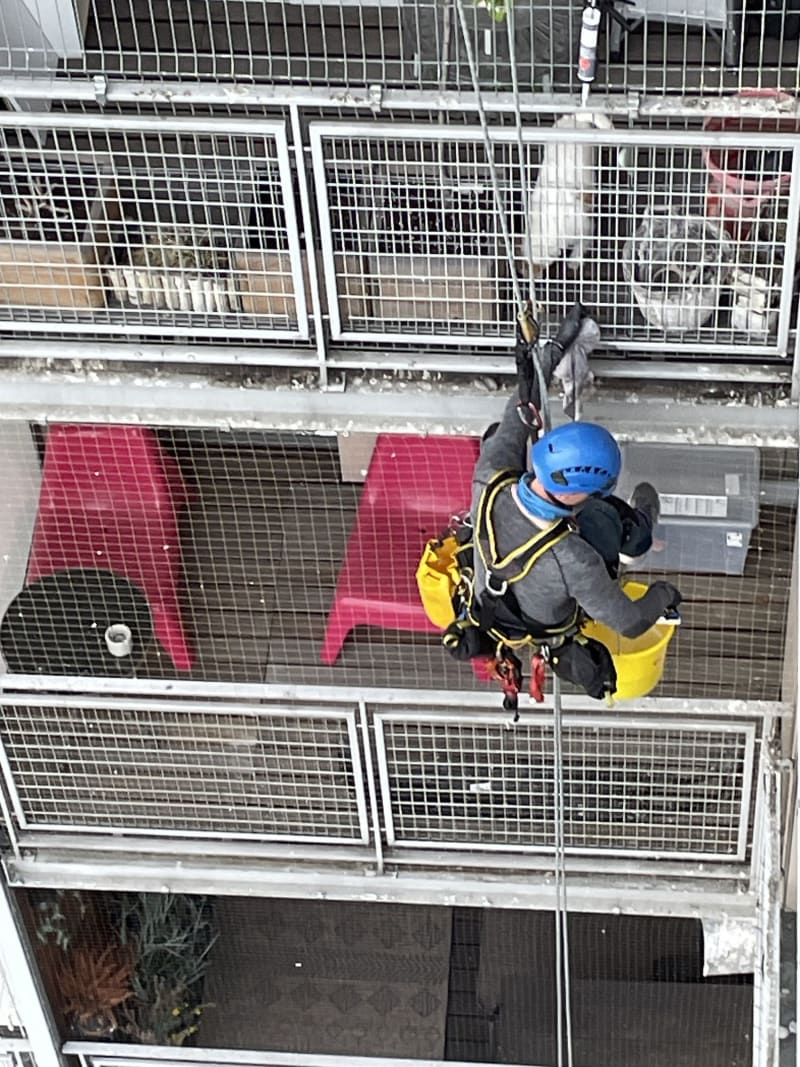 Alpinista na linie podczas prac na elewacji bloku