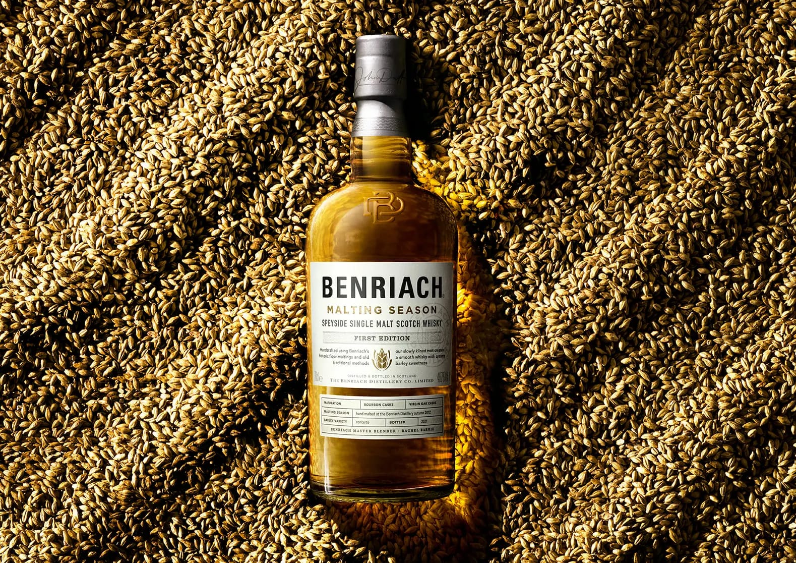 Two whisky glasses side by side on a wooden bar, one pale single grain, one amber single malt