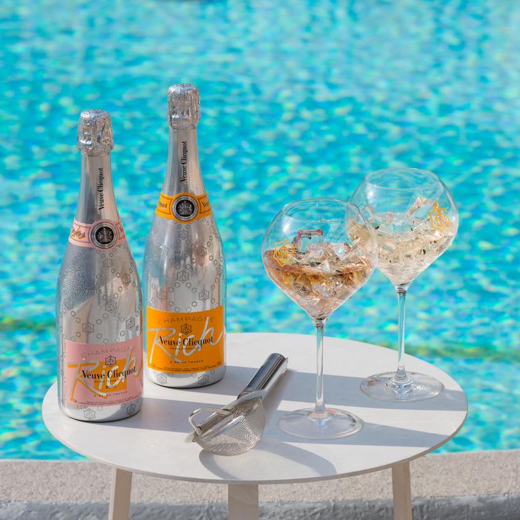 Two glasses of rosé champagne with ice and fruit garnish on a marble lounge table