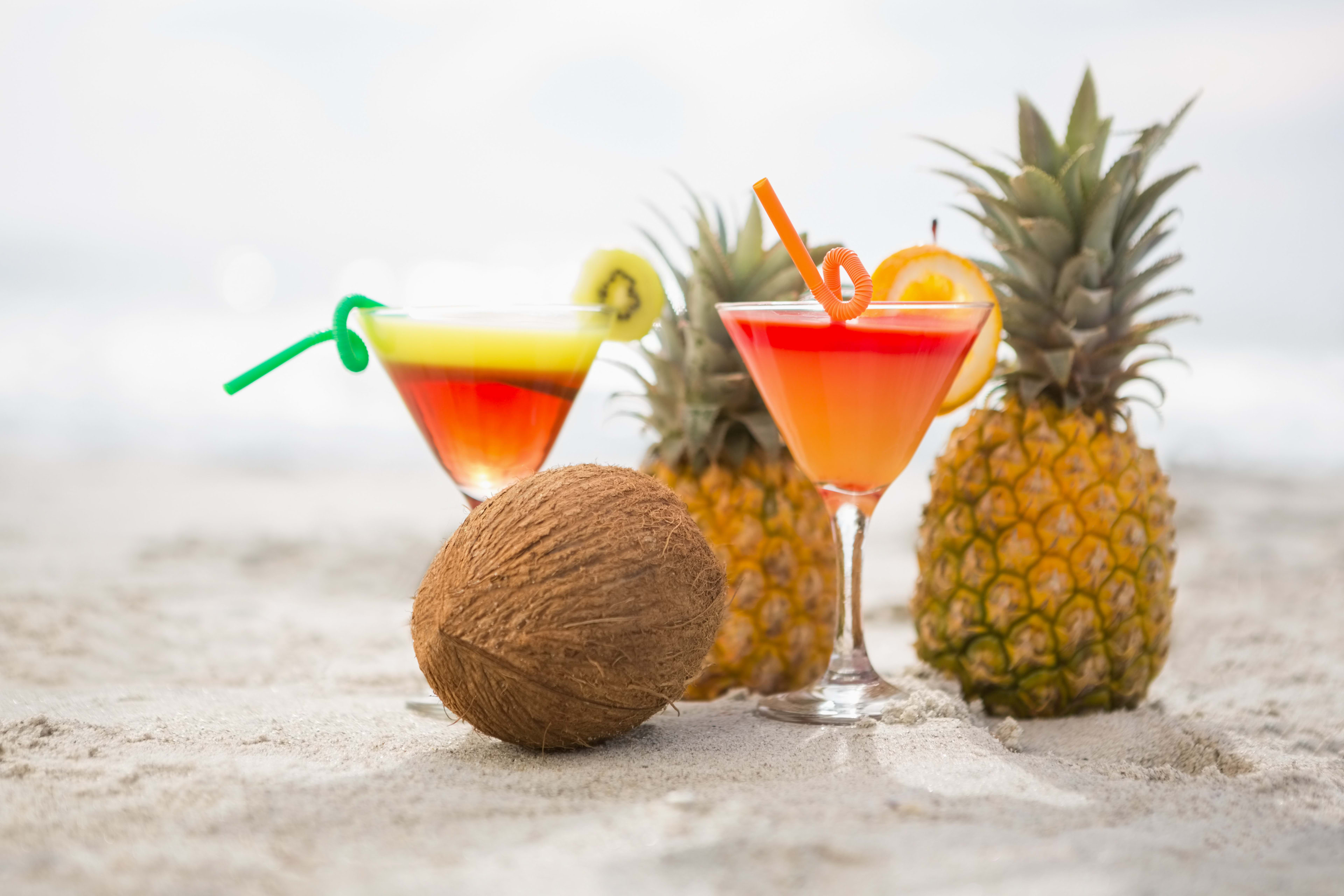 Tropical tiki cocktails with pineapple garnish and paper umbrellas on a colourful party table