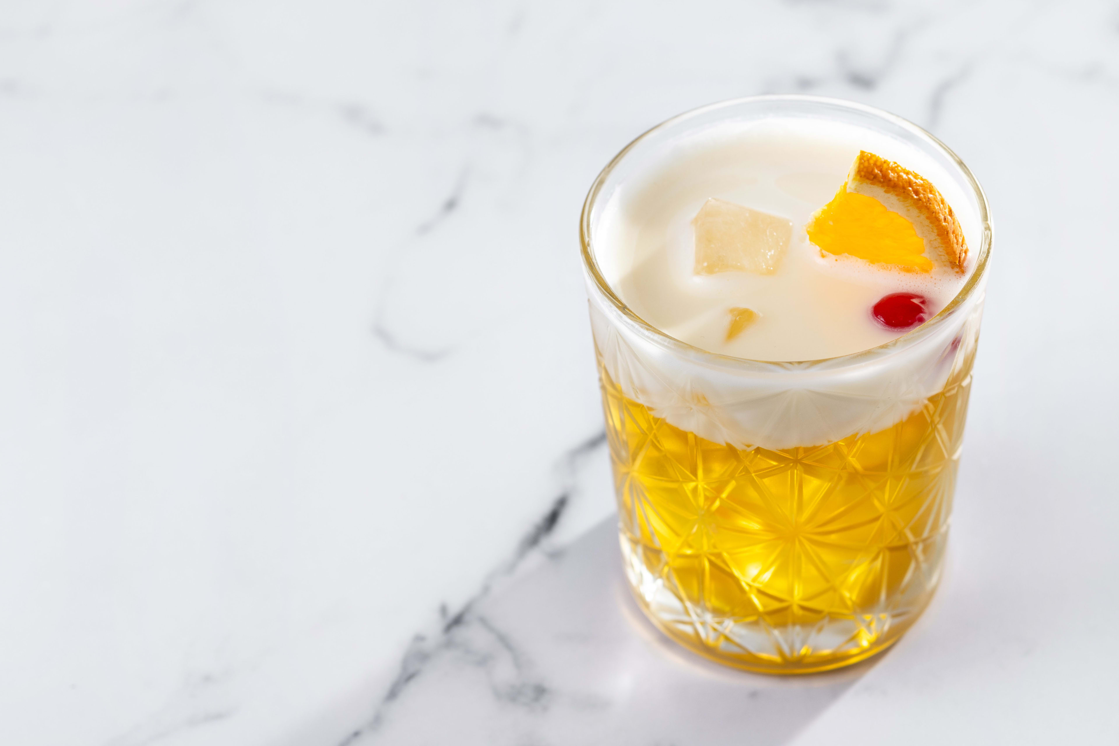 Three sour cocktails side by side — whiskey sour with egg white foam, watermelon margarita, cognac sour