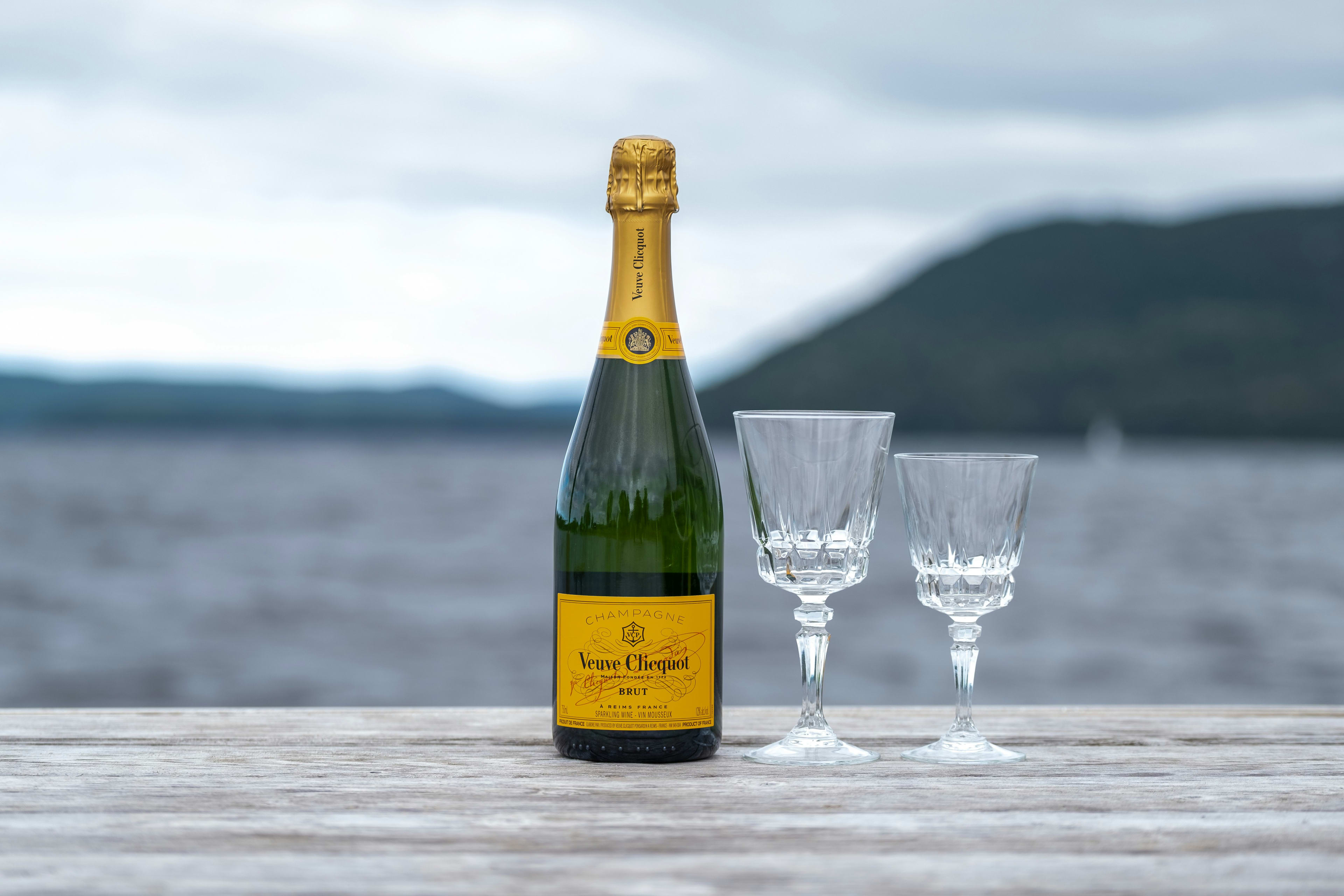 Two Champagne flutes beside Moët and Veuve Clicquot bottles on a Lagos rooftop at sunset