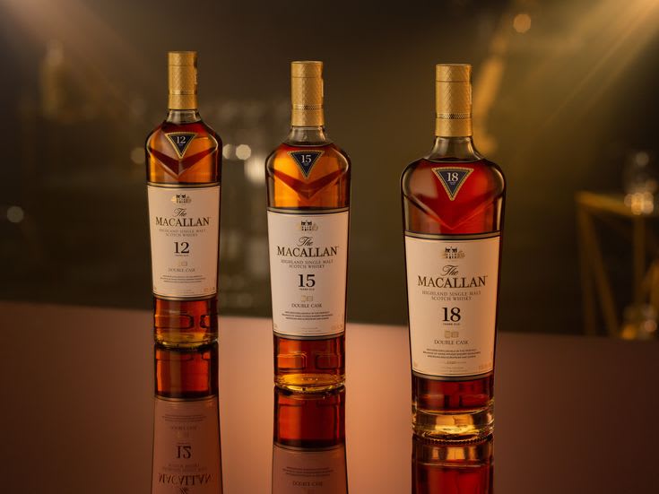 Three bottles of Macallan 12, 15, and 18 Year whisky lined up on a dark wooden bar