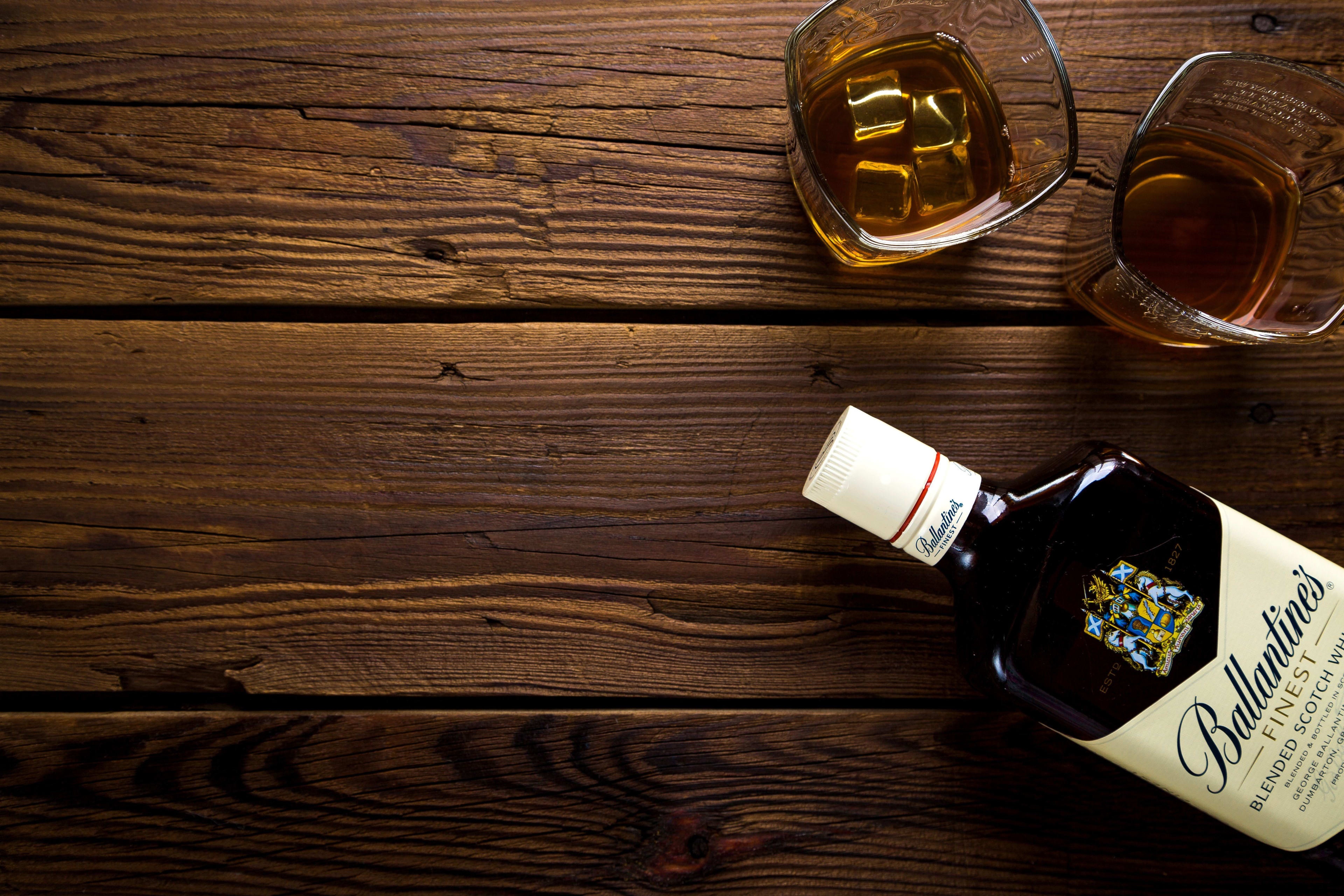Assorted whisky bottles arranged on a wooden bar counter with warm amber lighting