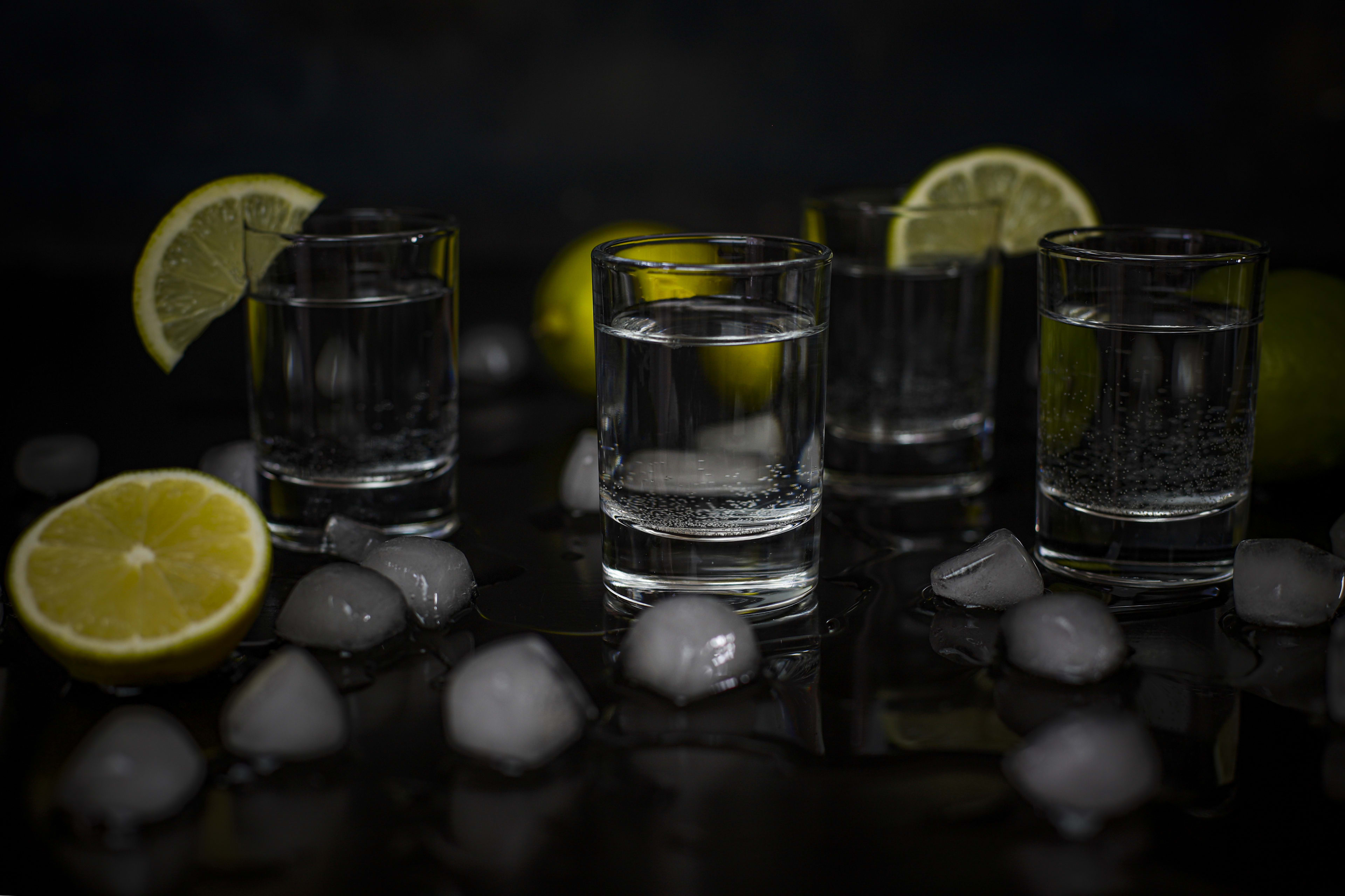 Two tequila glasses on the rocks with large ice cubes on a stylish bar top
