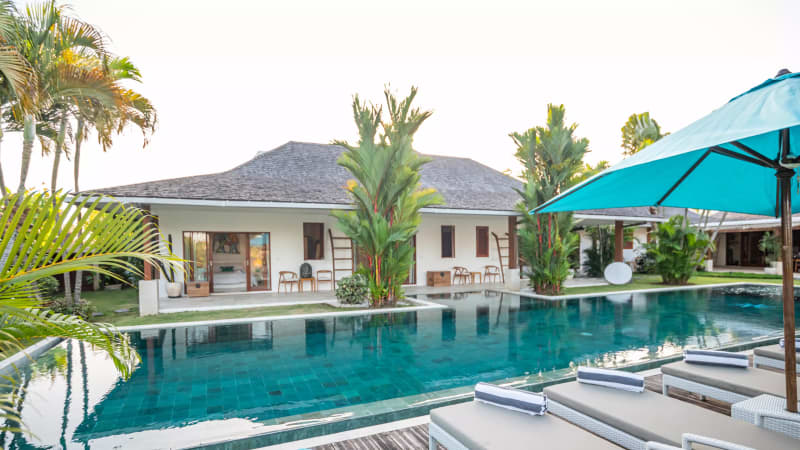The 25-metre private lap pool illuminated at night under tropical palms