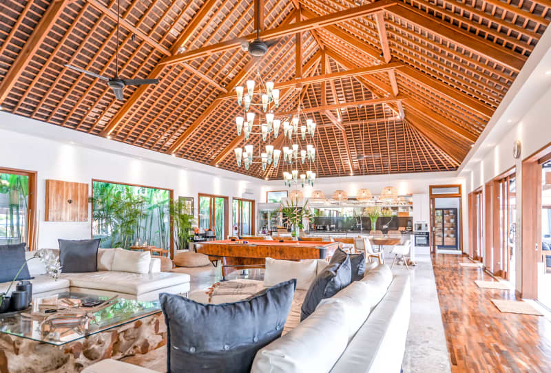 Grand open-plan living room with high vaulted timber ceilings and designer chandeliers