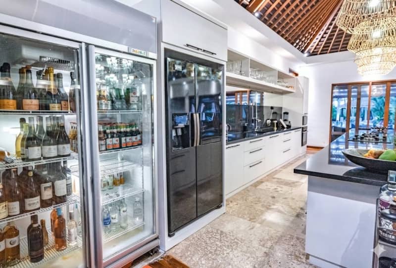 State-of-the-art gourmet kitchen with glass-fronted wine fridges and black marble island