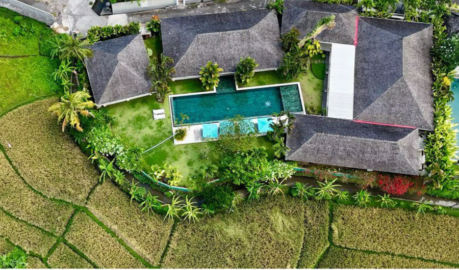 Aerial view of the villa showing the long swimming pool and surrounding rice fields