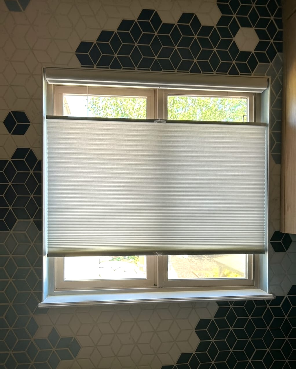 Top down/bottom up cellular shades in kitchen window surrounded by artistic tiles