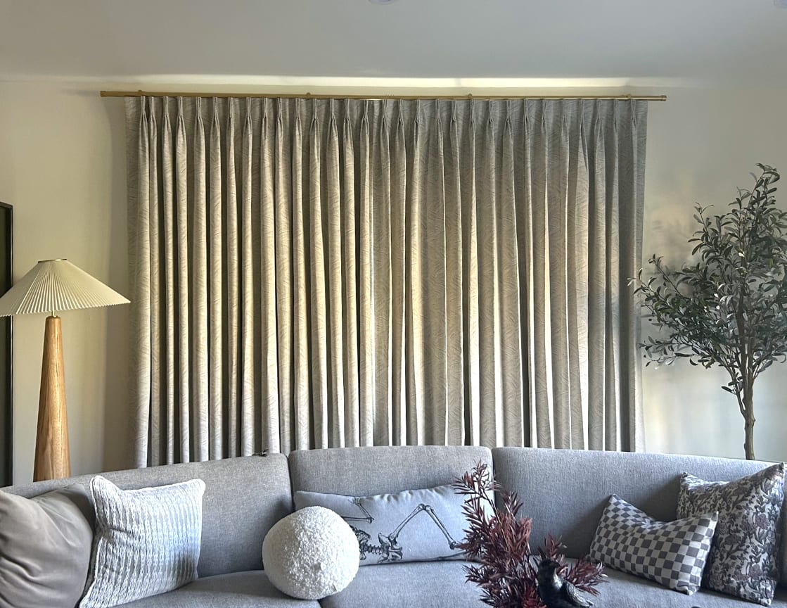 Neutral colored draperies in large living room window behind couch