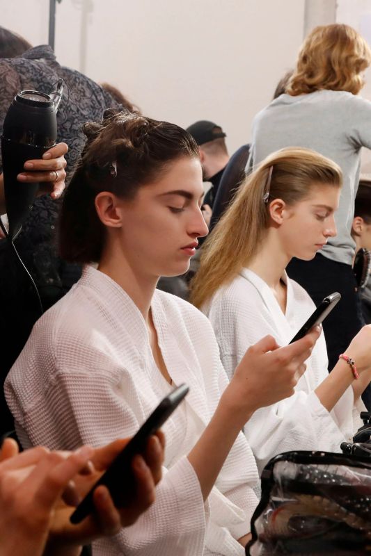 Une femme élégante réfléchit devant son téléphone, l’air lasse des applications de rencontre.