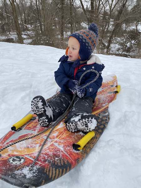 Toddler snowboots in the snow sledding