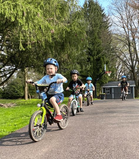 Kids all on bikes without training wheels riding down a hill