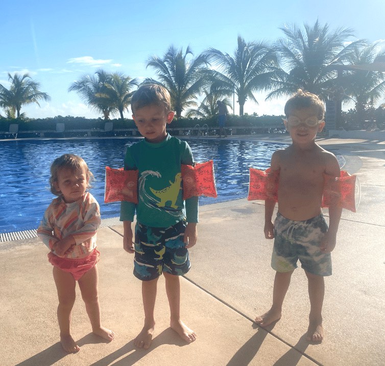 two kids in swim arm bands beside a pool in mexico