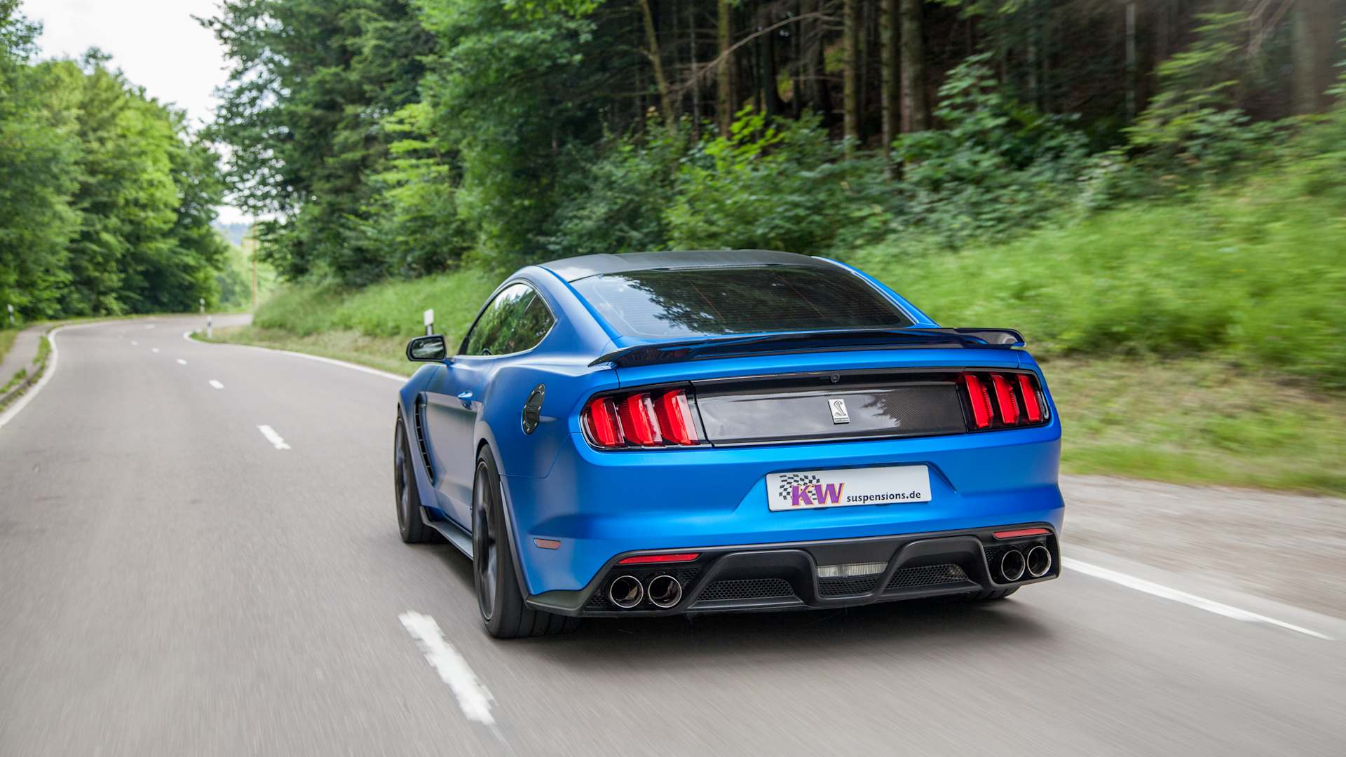 Heckansicht eines Ford Mustang (Typ LAE) auf einer Landstraße