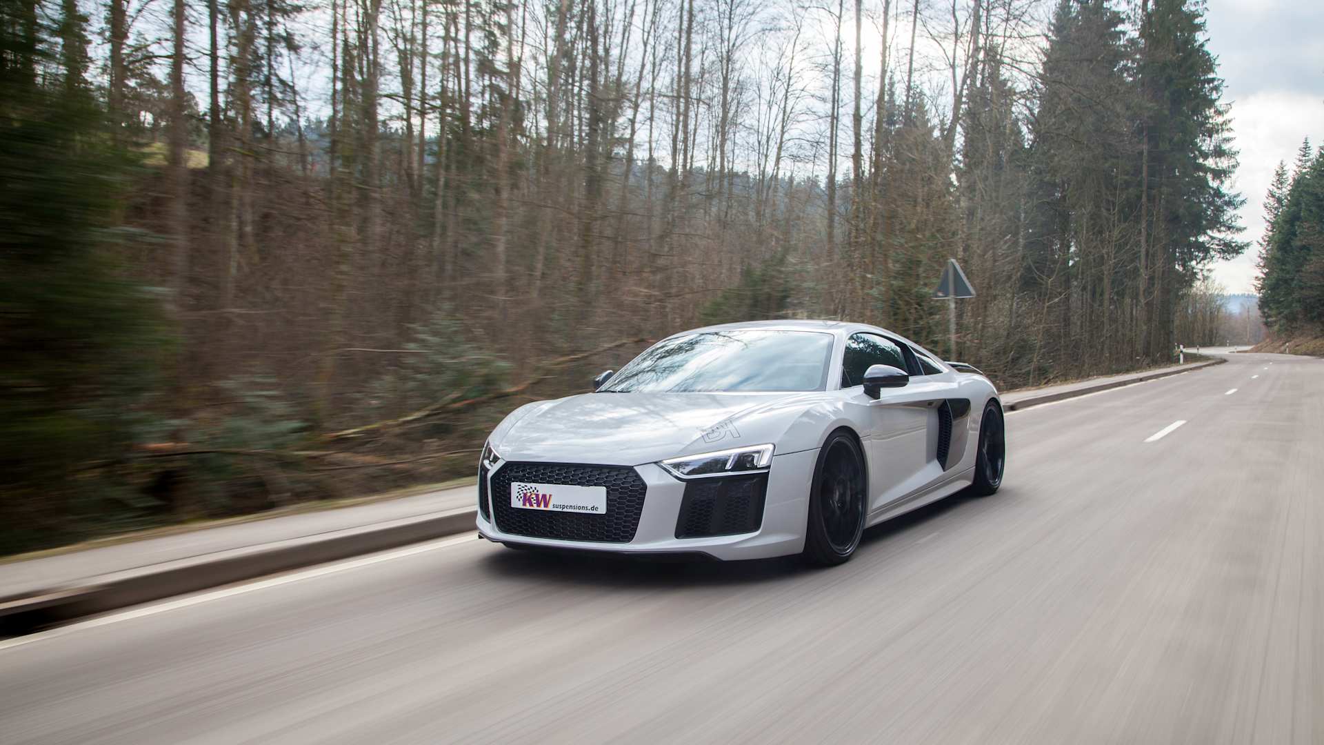 Grauer Audi R8 4S mit voller Fahrdynamik auf einer kurvenreichen Landstraße im Herbst