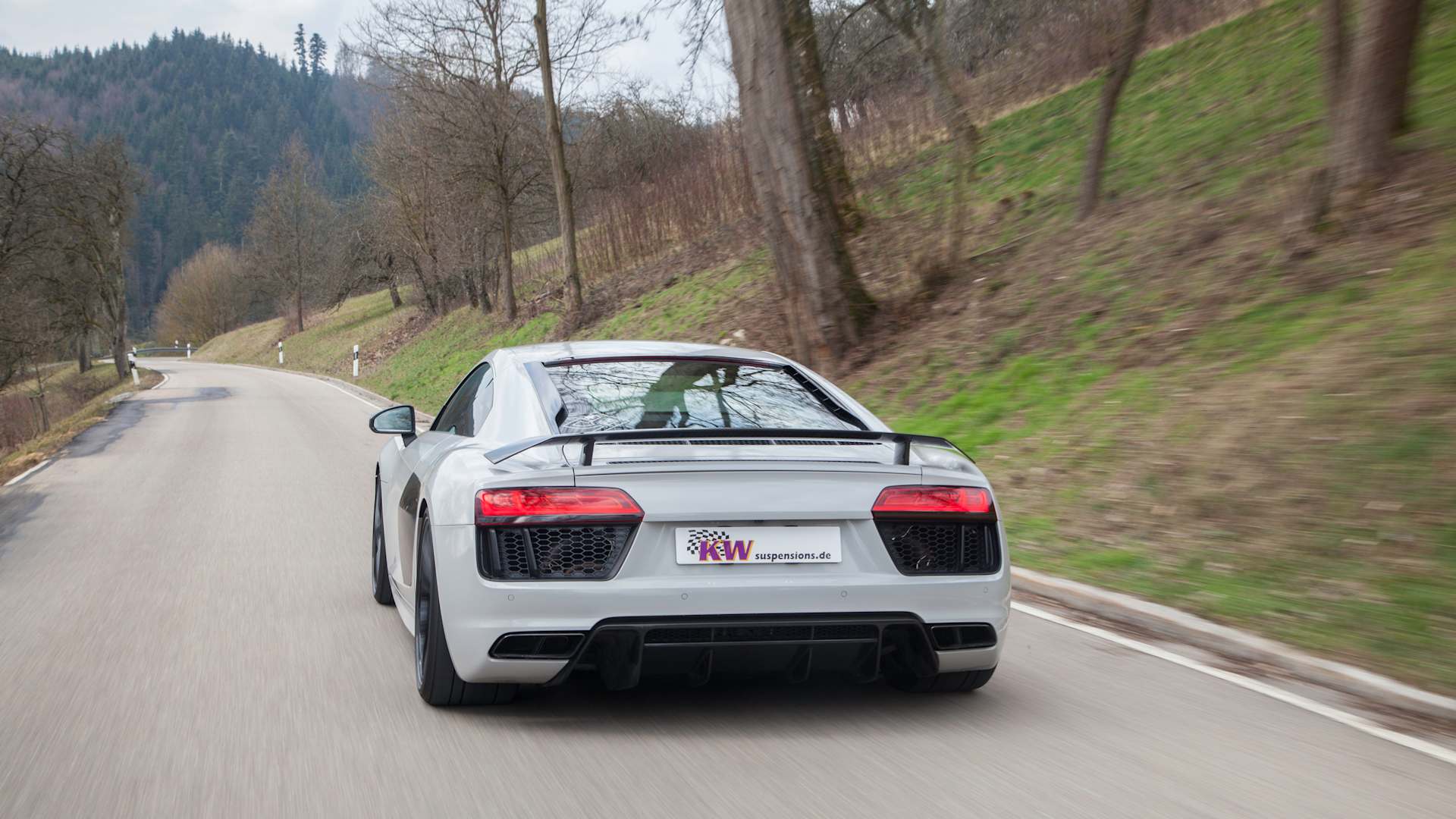 Ein grauer Audi R8 mit KW Gewindefahrwerk fährt auf einer Landstraße im Winter