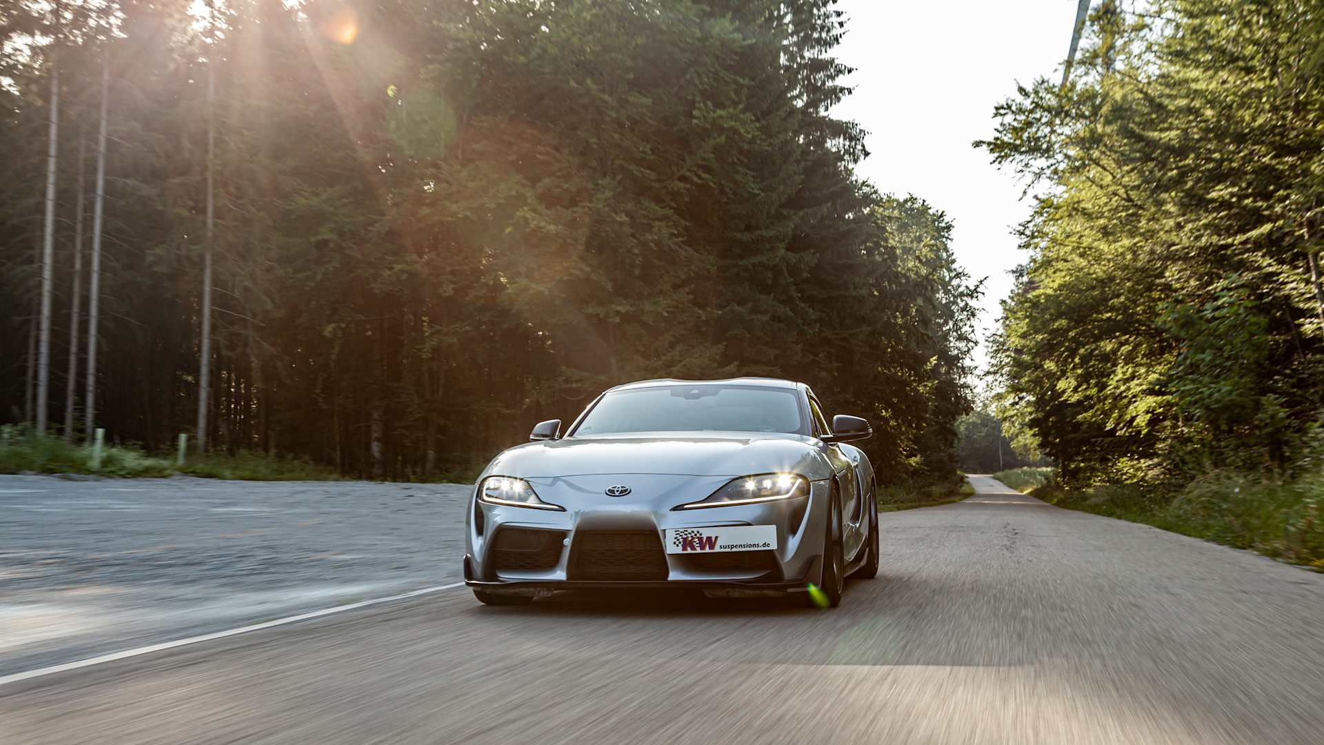 A Toyota GR Supra with KW coilovers in the evening sun on a country road in summer