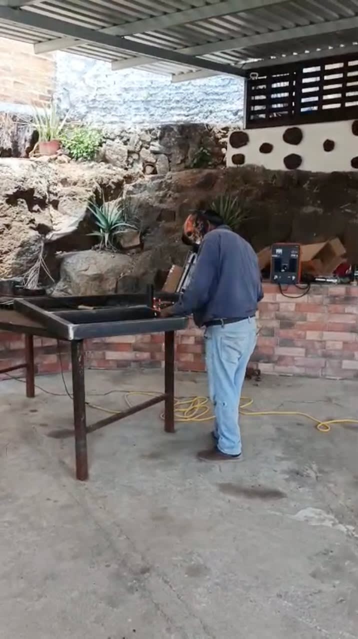 Empleado de GYM EN CASA SV soldando un equipo en el taller