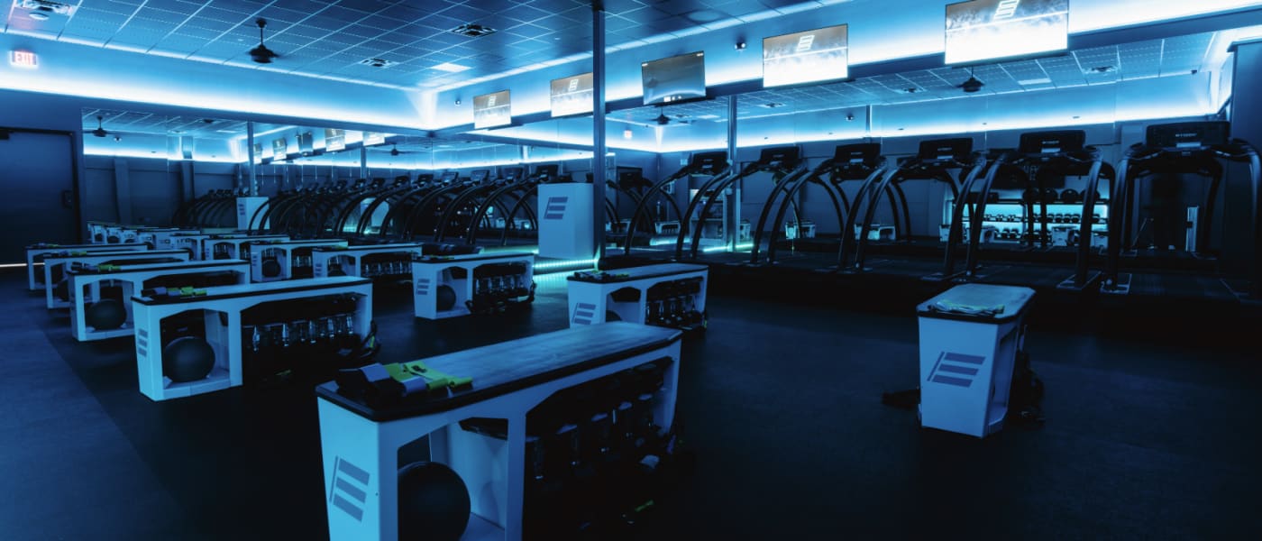 Inside a STRIDE Fitness studio: strength stations on the floor and treadmills along the wall