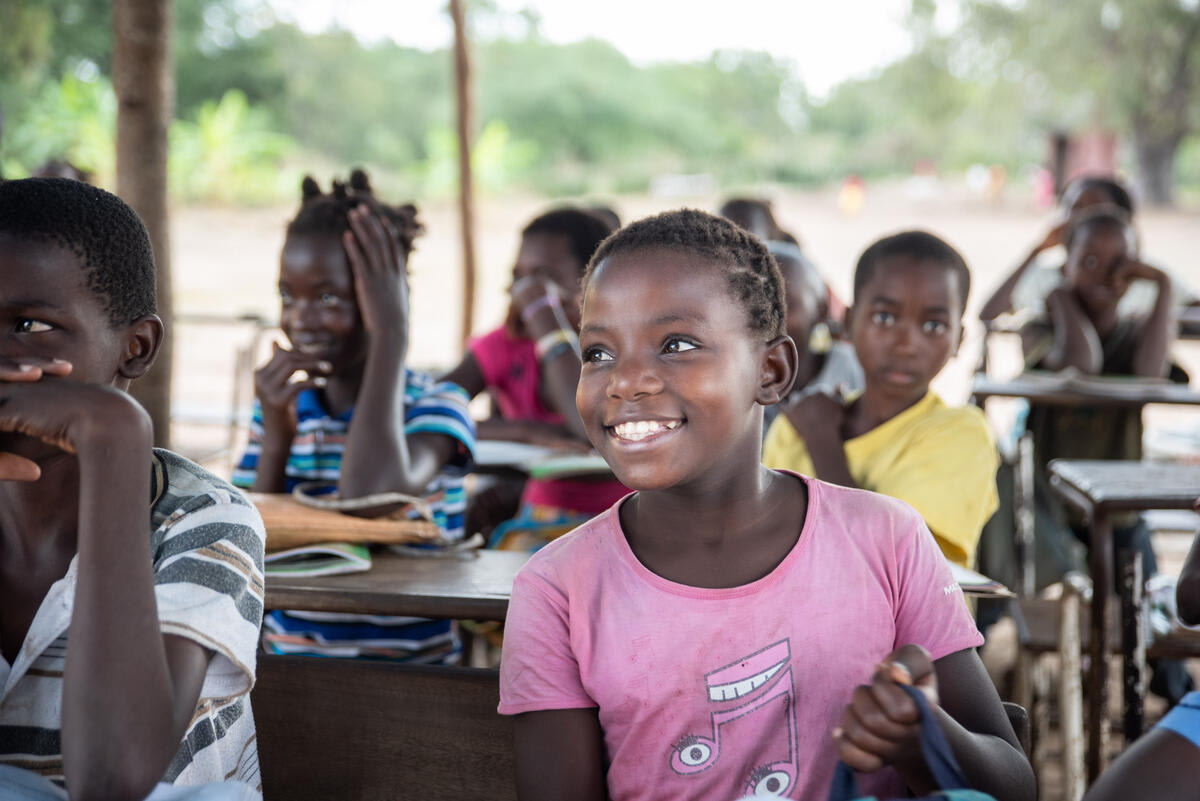 Billede af barn, der smiler og går i skole i Mozambique