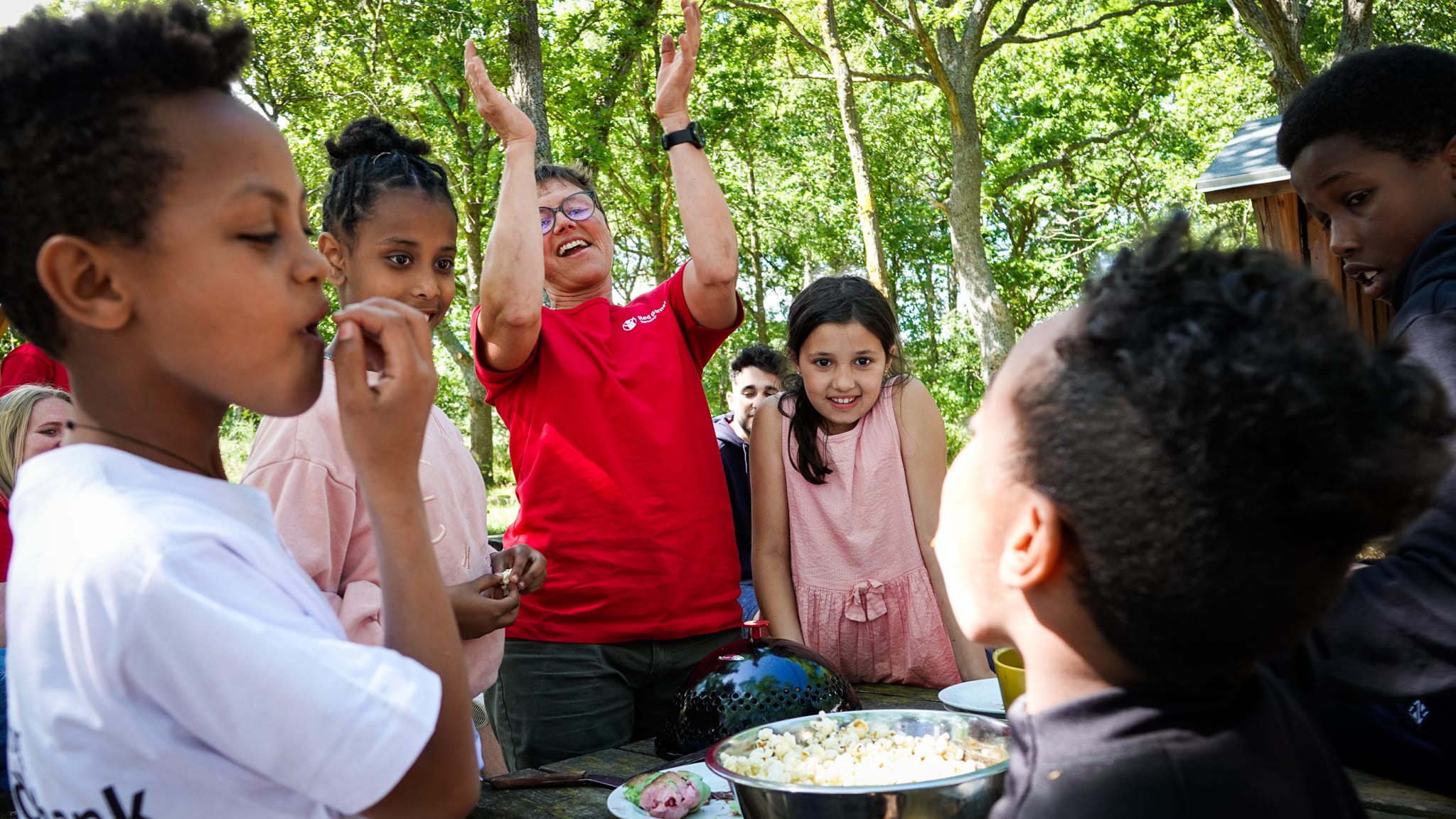 Børn og frivillig spiser popcorn på ferielejr