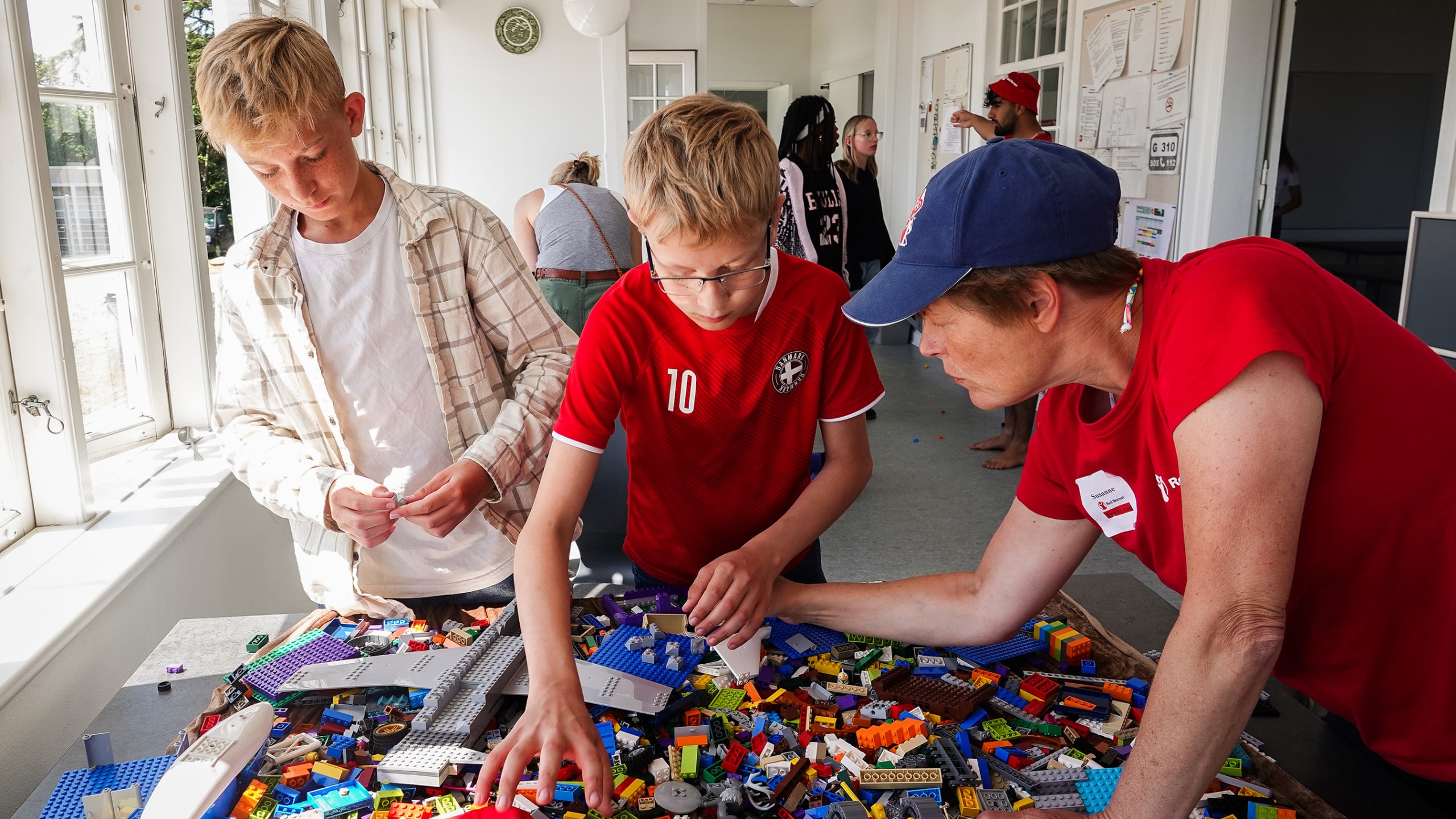 To børn og en frivillig leger med lego