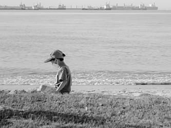 Billede af et barn, der går på en strand med en kasket på