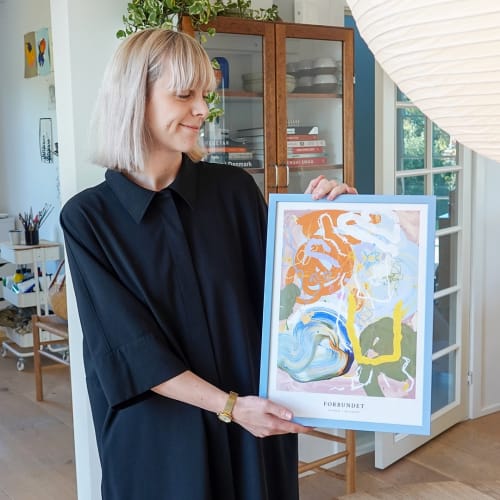 Ida Holm viser den farverige plakat frem