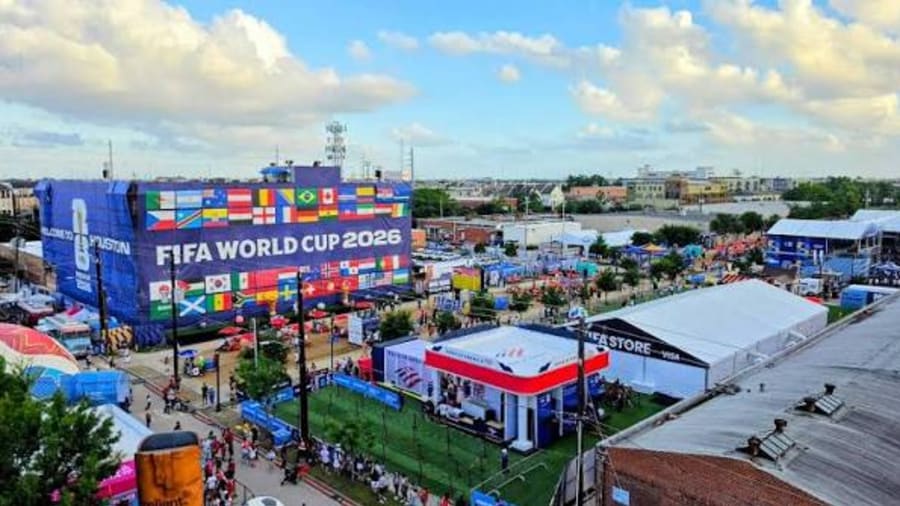An aerial view of a packed World Cup fan festival — food stalls, merchandise tents and crowds across the grounds