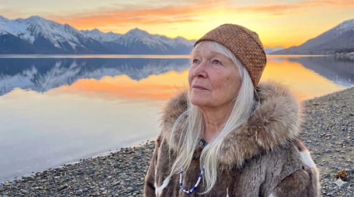 Native Alaskan woman at golden hour by a calm bay