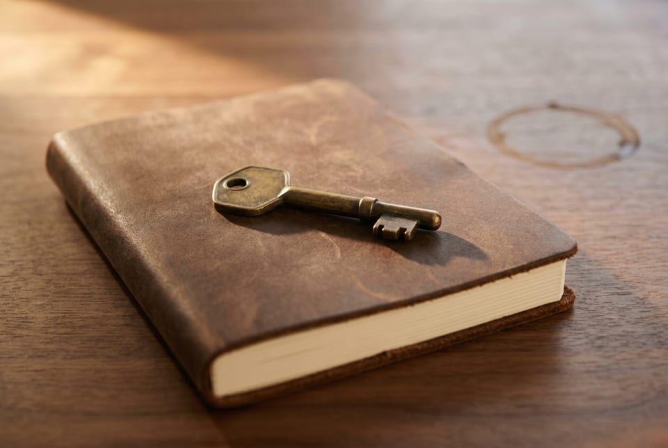 A brass key resting on a leather notebook in warm afternoon light.
