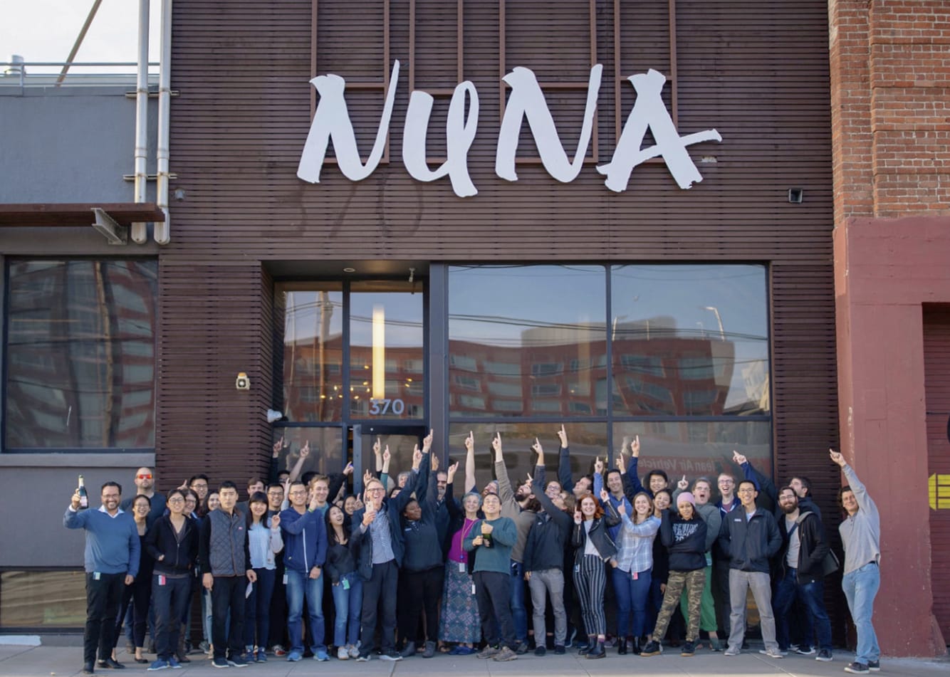 The Nuna team gathered and cheering outside the company's headquarters beneath the Nuna sign