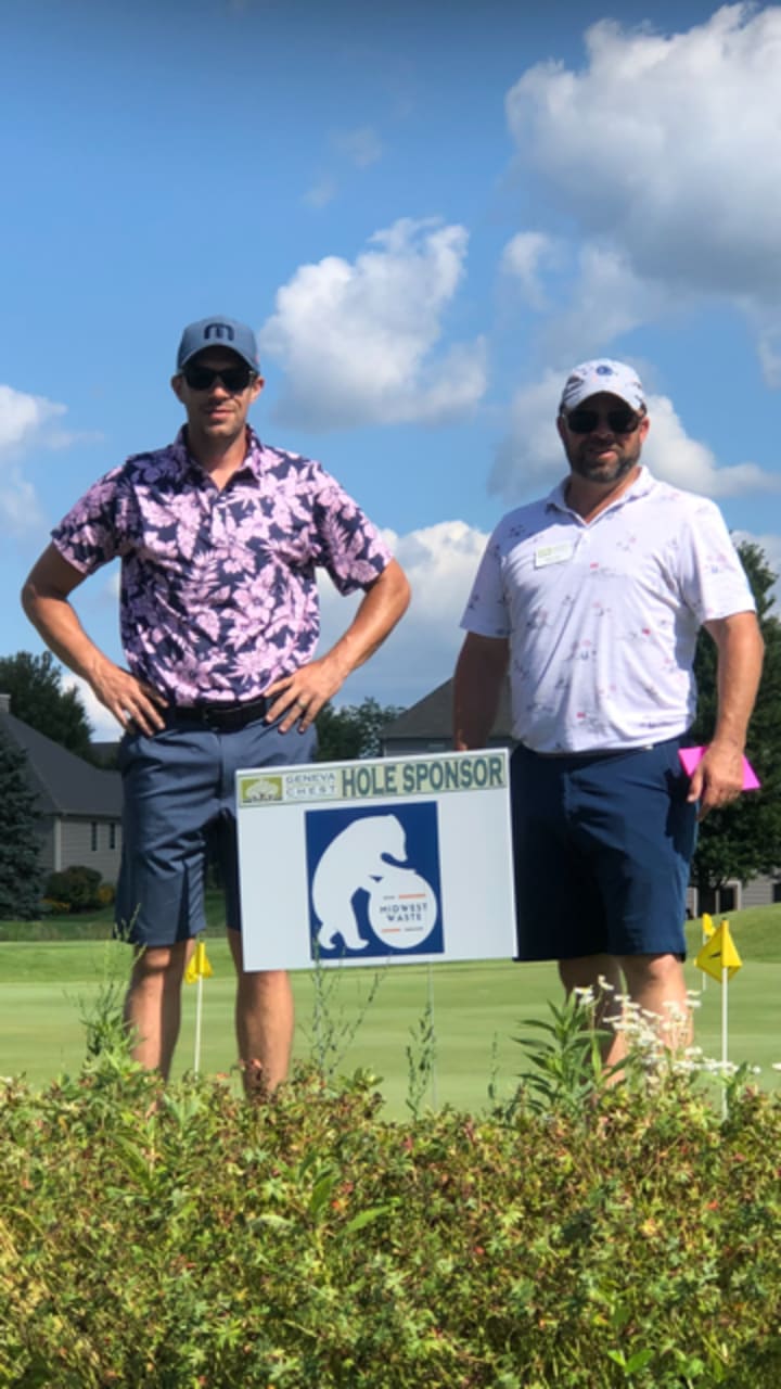 Greg Lower and Tyler Weber beside the Midwest Waste hole-sponsor board at a Geneva Golf Club outing