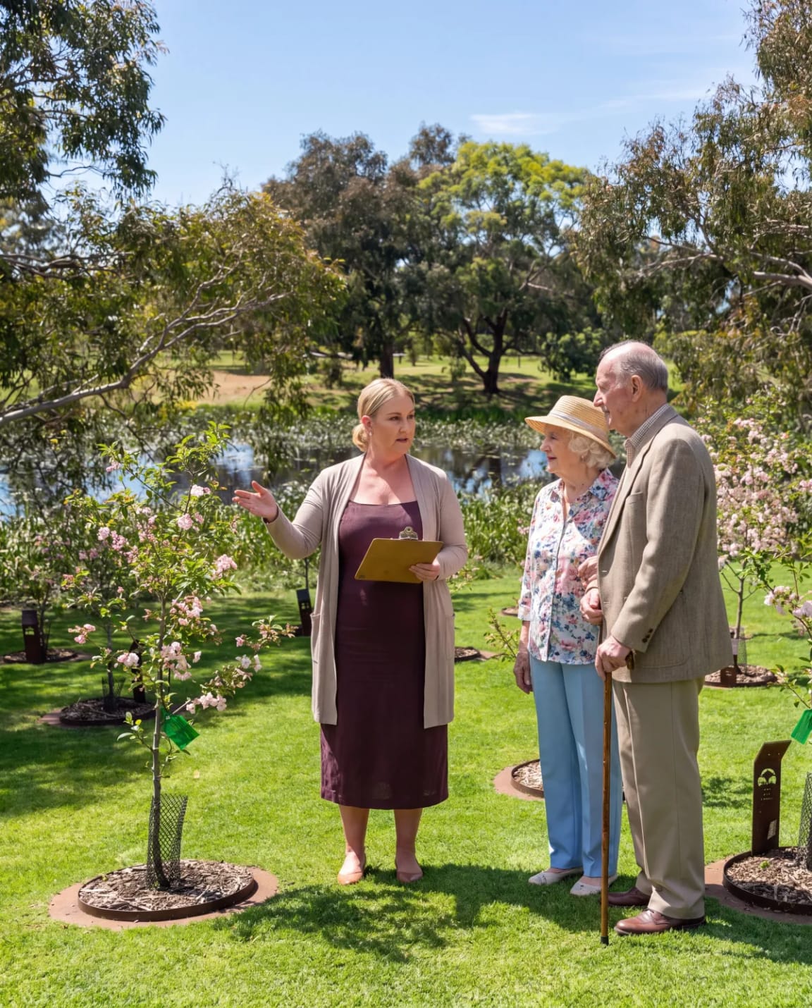 A Legacy Planner showing a senior couple a flowering memorial tree by the lake at Mornington Green.