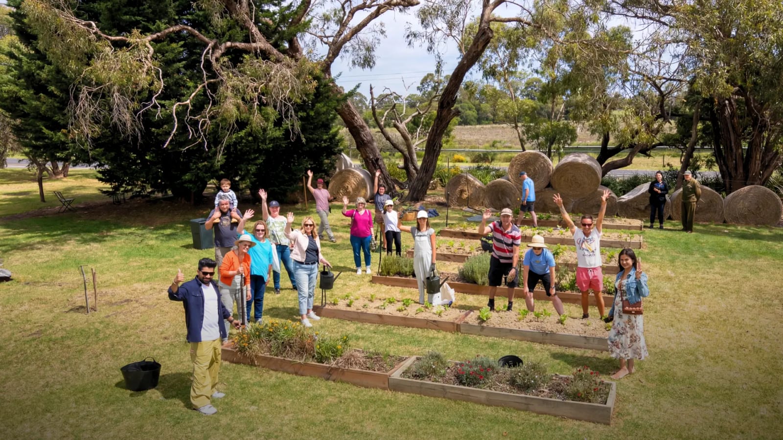 A group of people gathered in the Mornington Green memorial garden for a community flower planting event.