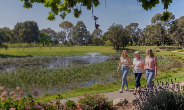Three generations of women walking together by the lake in the Mornington Green Living Legacy Gardens.