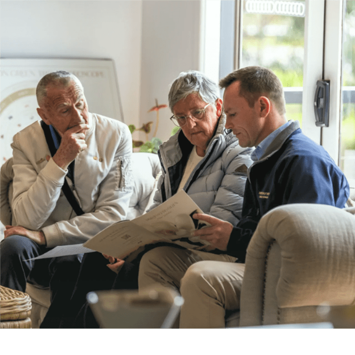 An older couple reviewing a Mornington Green brochure with a planner indoors.