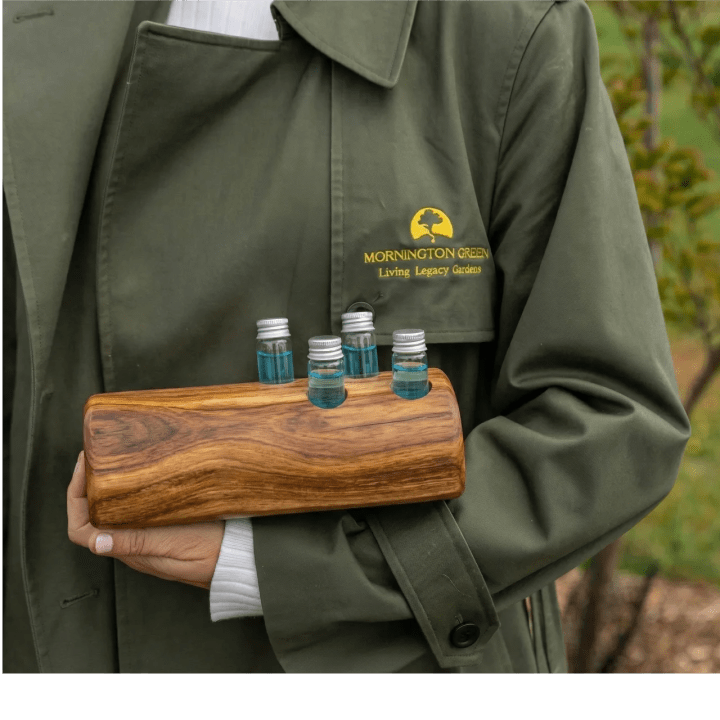 A Mornington Green staff member holding vials of the patented ash treatment in a wooden stand.
