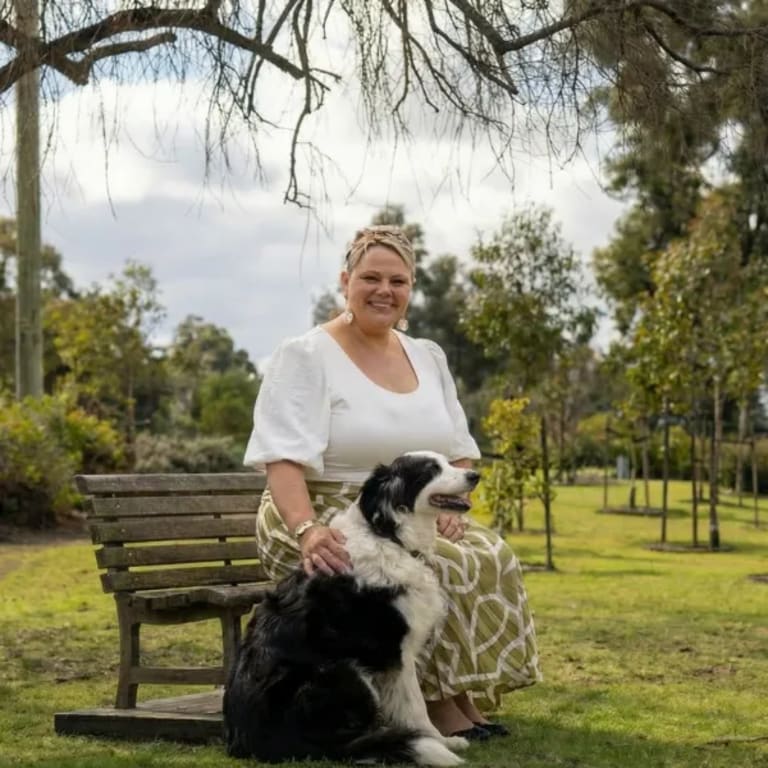 A woman sitting with her dog in the gardens at Mornington Green.