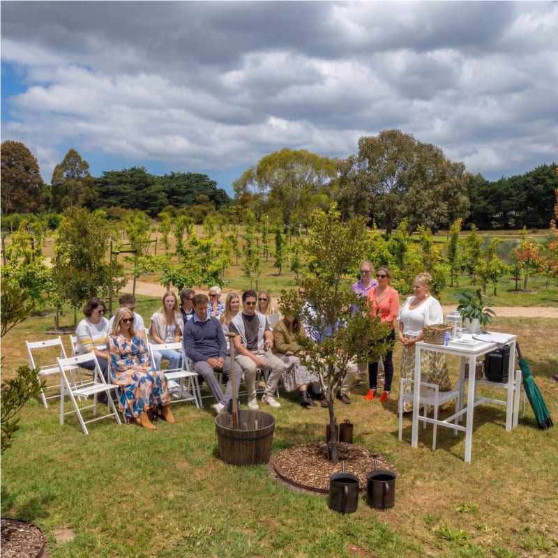 Family and friends gathered on white chairs for a tree planting ceremony in the Living Legacy Garden.